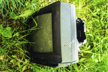 Çimenlerde eski retro tv. Gezegendeki çöpler. Doğal çevrenin kirlenmesi. Unutulmuş, cihazı, yerdışı kurtarın. Birisi sahada televizyonunu unutmuş..