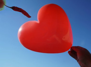 Mavi gökyüzü arka plan üzerinde kalp ve kuru shapr biber peper şeklinde Balon. 