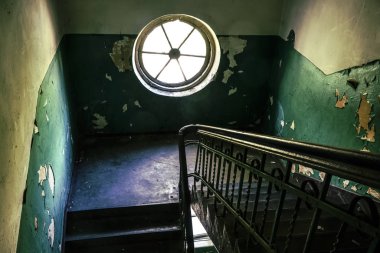 eski terk edilmiş binada demir ve ahşap merdivenler. Karanlık yangın çıkış merdiven pencere arka plan dokusundan ışık ile. gün ışığı ve yuvarlak pencere. 