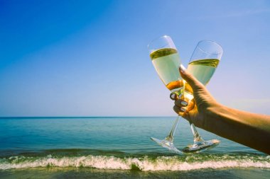 Kadın el akşam deniz dalgalarına karşı şampanya iki 2 bardak tutarak. Seçici odaklama, bulanık arka plan, metin alanı. boş kopyalama alanı