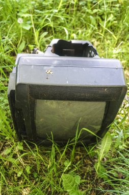 Çimenlerde eski retro tv. Gezegendeki çöpler. Doğal çevrenin kirlenmesi. Unutulmuş, cihazı, yerdışı kurtarın. Birisi sahada televizyonunu unutmuş..