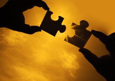 Gökyüzü arka planında yapboz parçaları olan eller. 