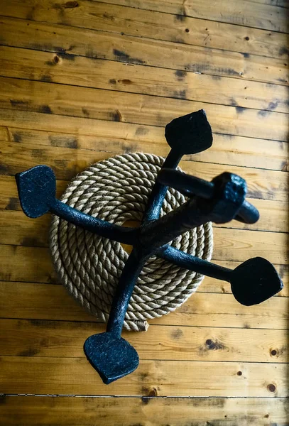 木地板上的黑色金属锚和绳子 — 图库照片
