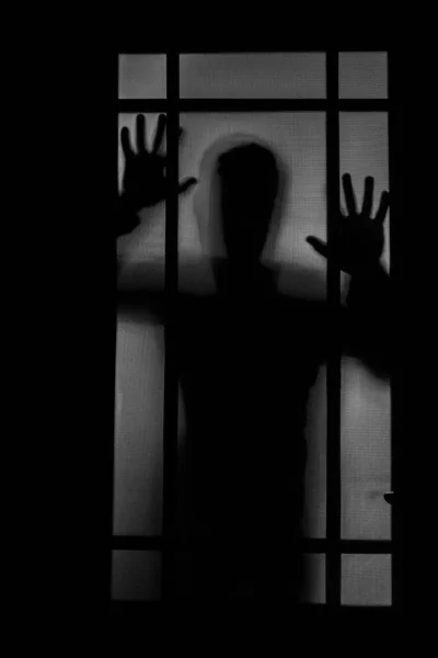 Person shadow on Frosted glass - violence concept background. shadow of a horror man. hands on glass.Dangerous male behind frosted glass.mystery Halloween background. Fear,terror,mystery