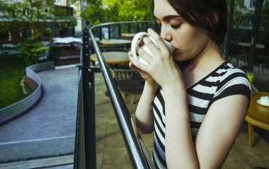Sakin sabah genç kız lüks otel balkonunda içecek manzarası zevk kahvaltı kahve içme rahatlatıcı, yaz seyahat tatilleri. Evde yaşam.