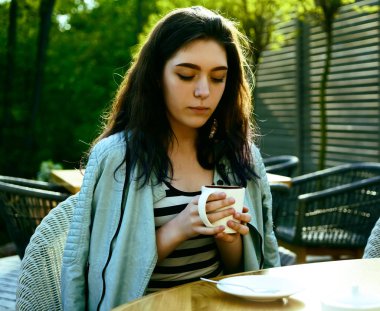 Kahve zamanı. Kaldırım kafede otururken kahve içen çekici genç kadın 