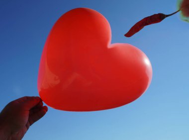 Mavi gökyüzü arka plan üzerinde kalp ve kuru shapr biber peper şeklinde Balon. 