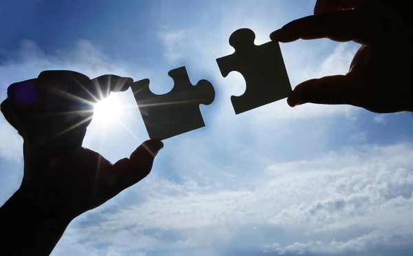 Two hands trying to connect couple puzzle piece with sunset back — Stock Photo, Image