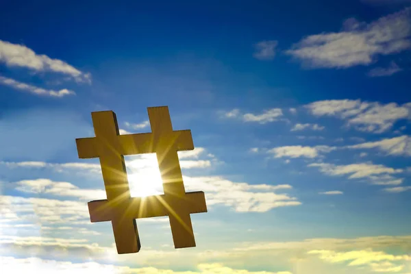 closeup of wooden sign in the shape of a hash tag symbol against the sky, with some blank space. hashtag