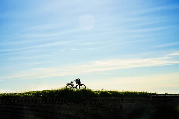 silhouette of one bike on blue sunset sky with clouds.   bicycle on heaven background. no people.