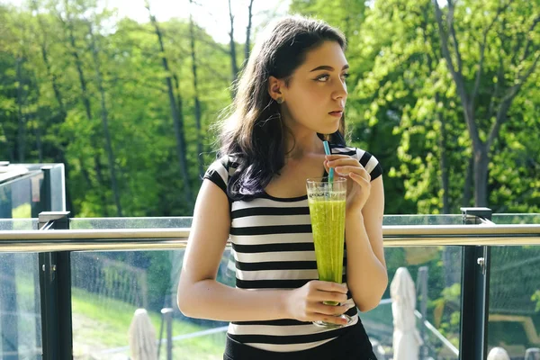 年轻女孩喝绿色鸡尾酒冰沙与稻草 女人在夏天喝蔬菜冰沙 健身与健康生活方式理念 户外肖像 — 图库照片