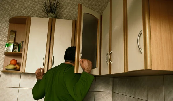 Молодой Человек Свитере Заглядывает Кухонный Шкаф Дома Смотрит Обратной Стороны — стоковое фото