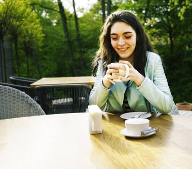 Kız kafenin balkonunda kahve fincan zevk. Sokak kafede kahve içen mutlu genç bayan Portresi. 