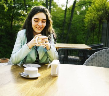 Kız kafenin balkonunda kahve fincan zevk. Sokak kafede kahve içen mutlu genç bayan Portresi. 