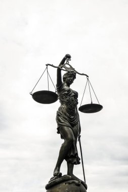 Adalet Figürü yakından kavramsal görünümünde mavi gökyüzü arka plan üzerinde hukukun ölçekleri tutan bir göz bağı giyen