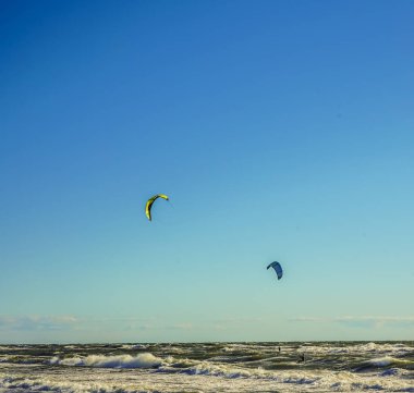 Mavi gökyüzü arka plan karşı uçurtma ile Surfers. Baltık denizinde sahilde iki sörfçü .2 deniz arka planda uçurtma sörfçü.