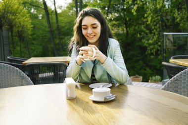 Kız kafenin balkonunda kahve fincan zevk. Sokak kafede kahve içen mutlu genç bayan Portresi. 
