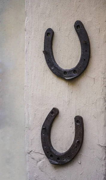 two rusty horseshoes hang on concrete wall background.