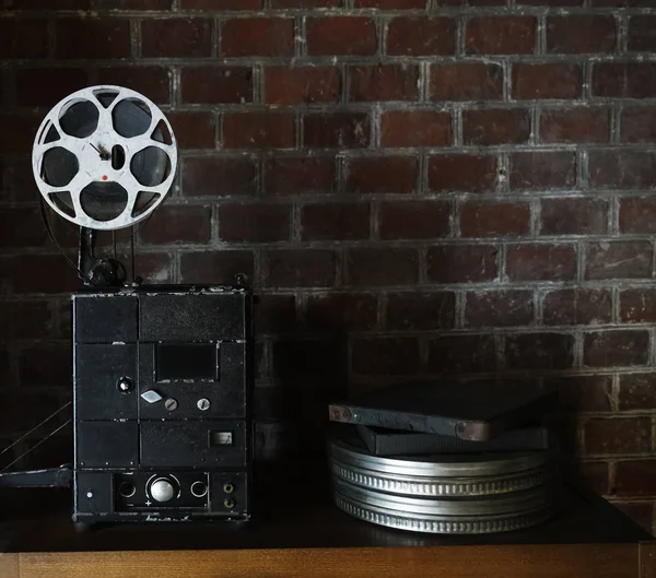 photo of an old movie projector on brick wall background. Old style movie projector, still-life, close-up.