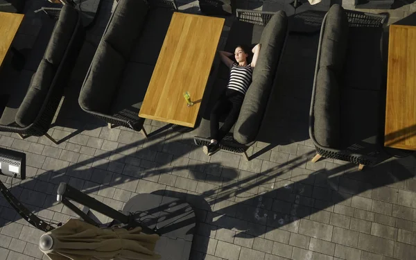 Young Beautiful Woman Sleeping On Sofa At cafe on balcony. Top view of a cute smiling young girl lying on a couch.