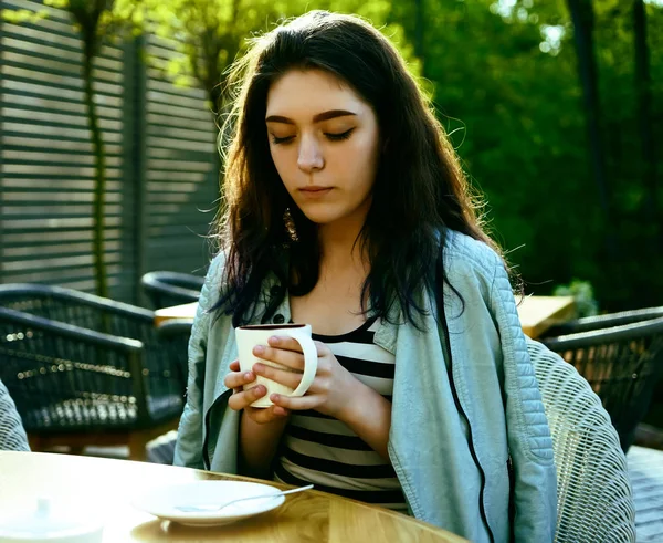 Kahve zamanı. Kaldırım kafede otururken kahve içen çekici genç kadın 