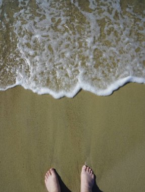 Deniz kumu üzerinde ayaklar ve fotokopi alanı ile dalga, okyanus sahilinde tatil, yaz tatili.