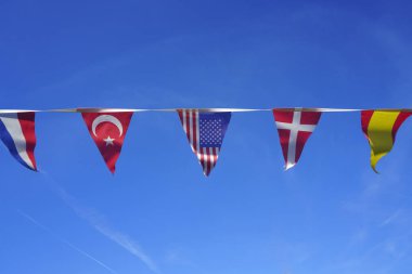  mavi gökyüzü arka plan karşı üçgen Hollandaca, Türk, Amerikan, Norveç ve İspanyol bayrakları. Dünya bayrakları seti