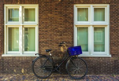 Avrupa'da bir siyah retro bisiklet ile beyaz pencereler. Bisiklet kırmızı tuğla duvara yaslanmış. ön görünüm. Hollanda, Haarlem. Hollanda