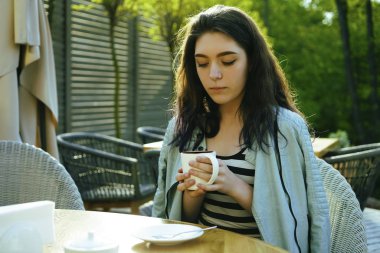 Kahve zamanı. Kaldırım kafede otururken kahve içen çekici genç kadın 