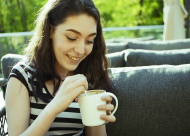 Kız kafenin balkonunda kahve fincan zevk. Sokak kafede kahve içen mutlu genç bayan Portresi. 