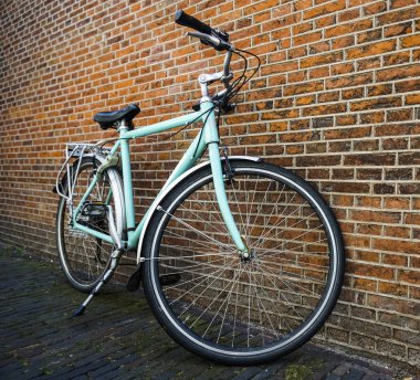 Kırmızı tuğla duvar yakınında duran sepet olmadan Mavi vintage şehir bisikleti.