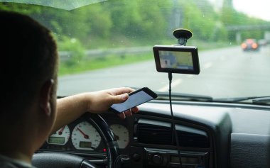 Berlin, Almanya - 26 Nisan 2019: Arabanın ön koltuğunda oturan akıllı telefon kullanan adam. Ekrana odaklanmış arka görünüm.  