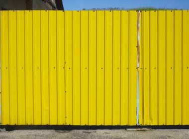 demir kapı. Eski çinko sarısı renk. Sarı oluklu çitdoku arka plan.