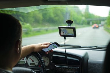 Berlin, Almanya - 26 Nisan 2019: Arabanın ön koltuğunda oturan akıllı telefon kullanan adam. Ekrana odaklanmış arka görünüm.  