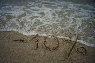 okyanusa yakın kum üzerinde yazıt eksi yüzde on. Denizde tatilde indirim. -10%. kum üzerinde yazıt eksi yüzde 10