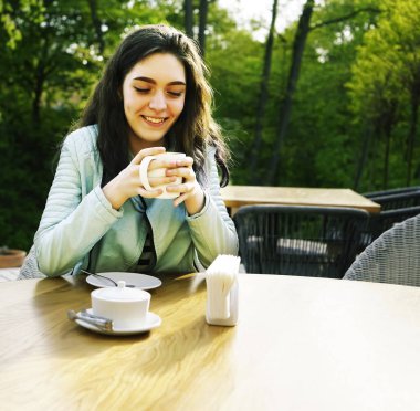 Kız kafenin balkonunda kahve fincan zevk. Sokak kafede kahve içen mutlu genç bayan Portresi. 