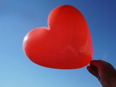 Mavi gökyüzü arka planda kalp şeklinde balon. 