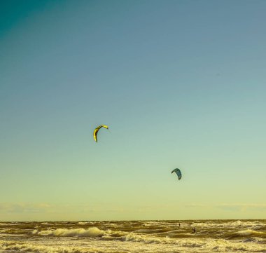 Mavi gökyüzü arka plan karşı uçurtma ile Surfers. Baltık denizinde sahilde iki sörfçü .2 deniz arka planda uçurtma sörfçü.