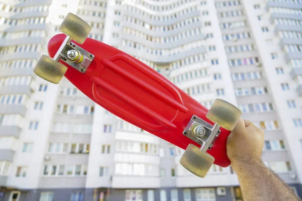 Skater Mão Segurando Deck Skate Vermelho Fundo Casa Branca — Fotografia de Stock