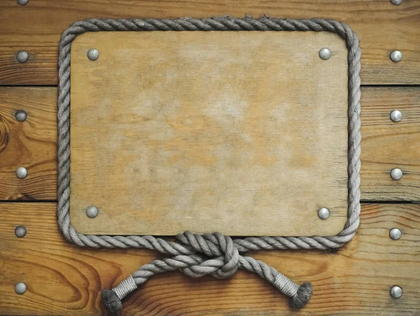 close up of an empty wooden sign with rope around on wooden boards background