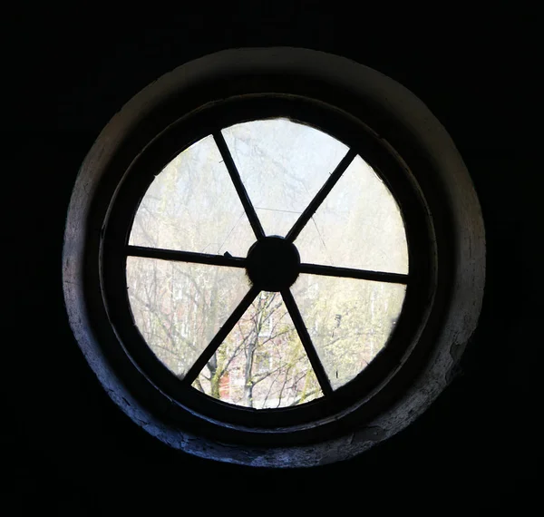 Broken glass old oval or round window frame.  Old house background: circle window at the wall. interior background.