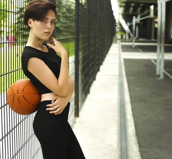 Sporty caucasian girl playing basketball - short haircut