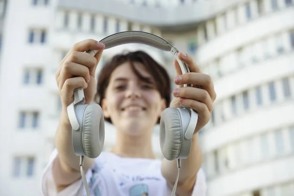 Hermosa Joven Sosteniendo Las Manos Auriculares Blancos Sonriendo — Foto de Stock