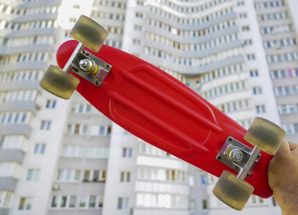 Skater Mão Segurando Deck Skate Vermelho Fundo Casa Branca — Fotografia de Stock