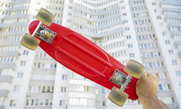 Skater Mão Segurando Deck Skate Vermelho Fundo Casa Branca — Fotografia de Stock