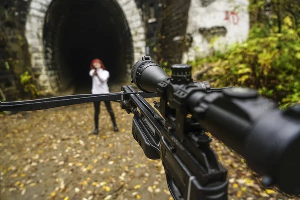 woman shooting with bow and arrow. crossbow and gun on belt. girl with gun opposite.