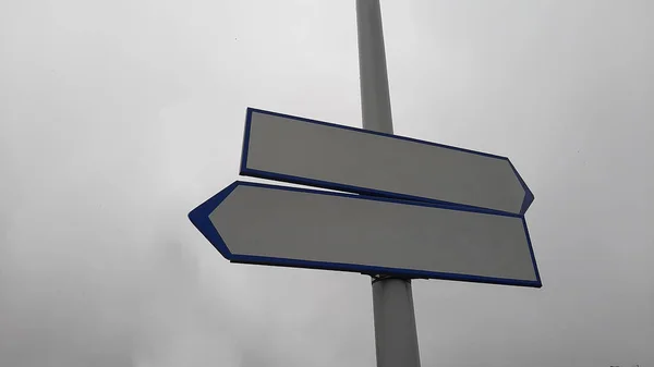 Two blank road signs pointing in opposite directions, blue sky background in vintage style.