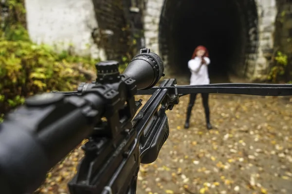 woman shooting with bow and arrow. crossbow and gun on belt. girl with gun opposite.