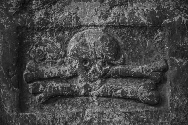 Ancient destroyed terrible sculpture of a skull and crossed bones. baroque sculpted marble skull and bones ornament