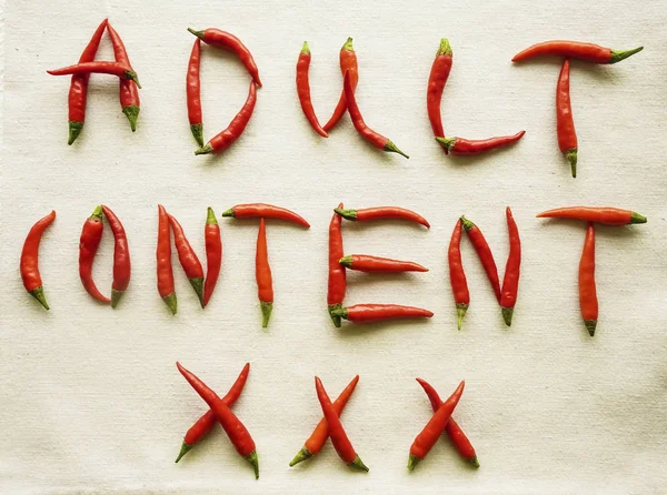 Words - adult content xxx written from red hot pepper letters isolated on white background